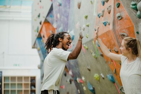 Two young adults rock climbing during recreation therapy.